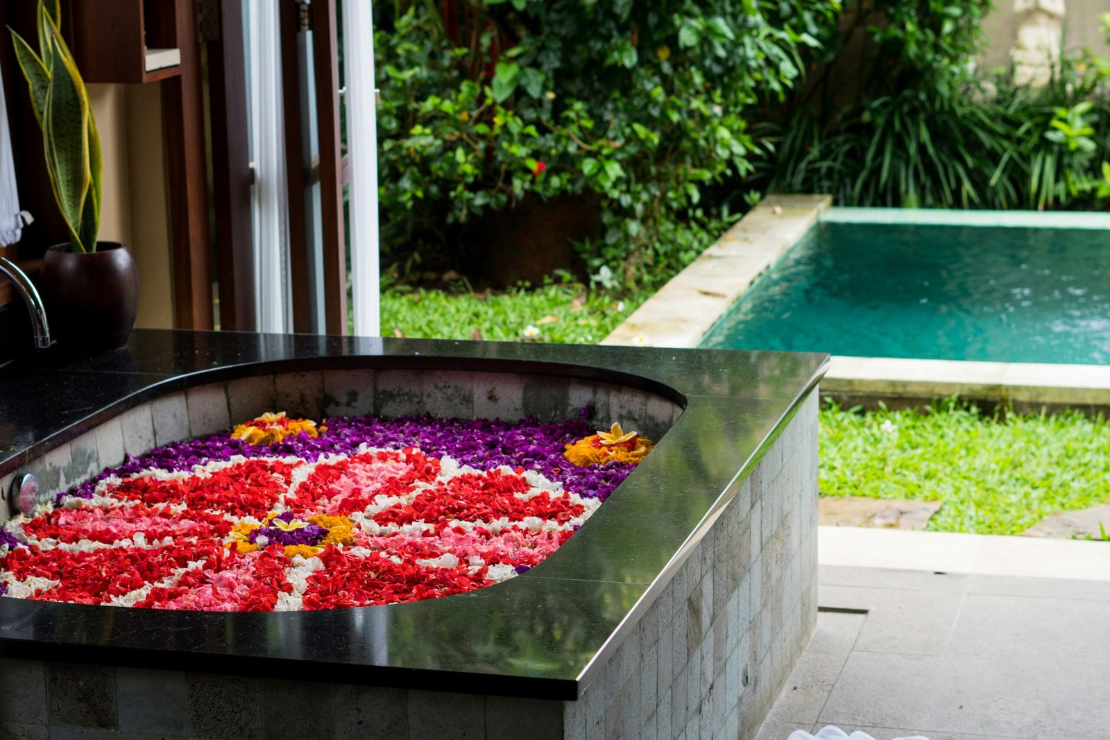 a pool with flowers in it next to a house